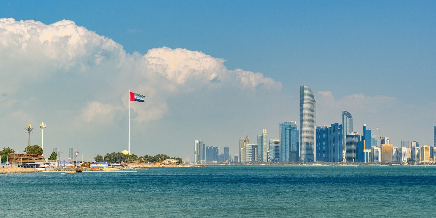 Abu Dhabi, UAE - January 3, 2025: A stunning view of the Abu Dhabi skyline with the UAE flag prominently displayed, highlighting the city's modern architecture and coastal beauty.