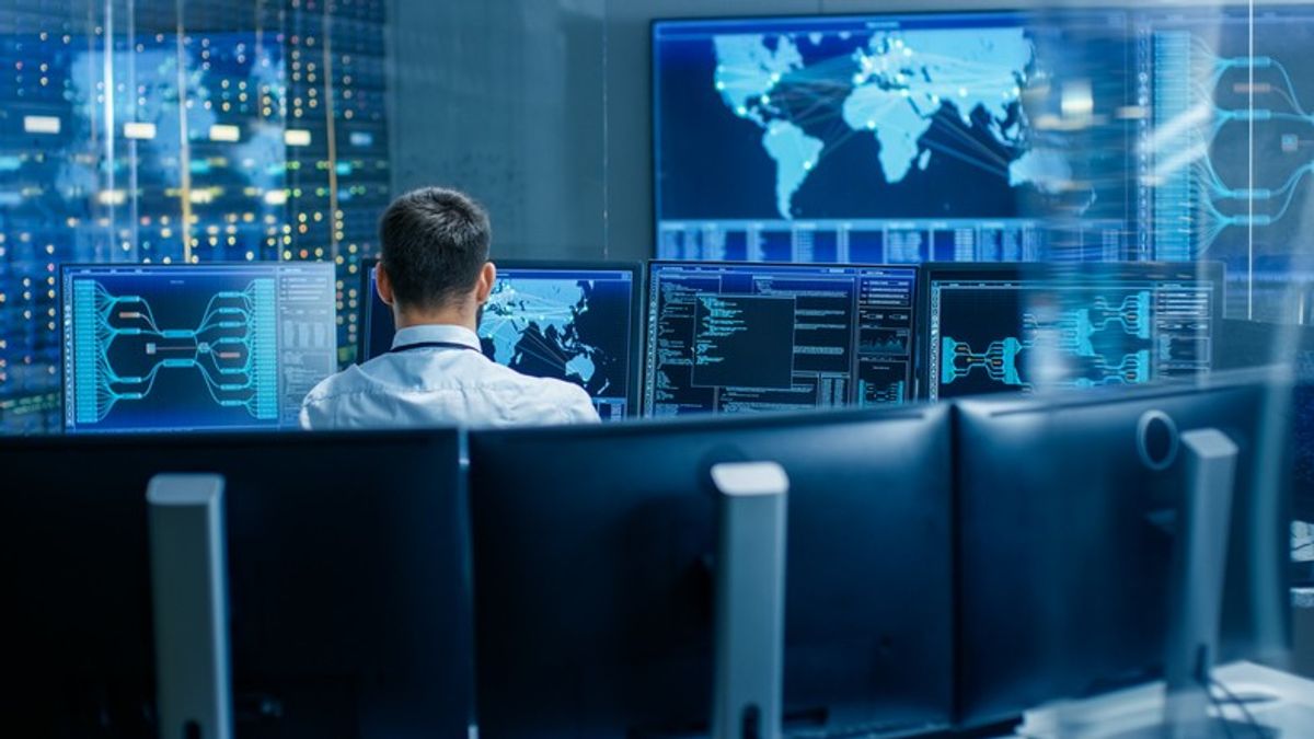 <p>Back View in the System Control Center Operator Working. Multiple Screens Showing Technical Data.</p>