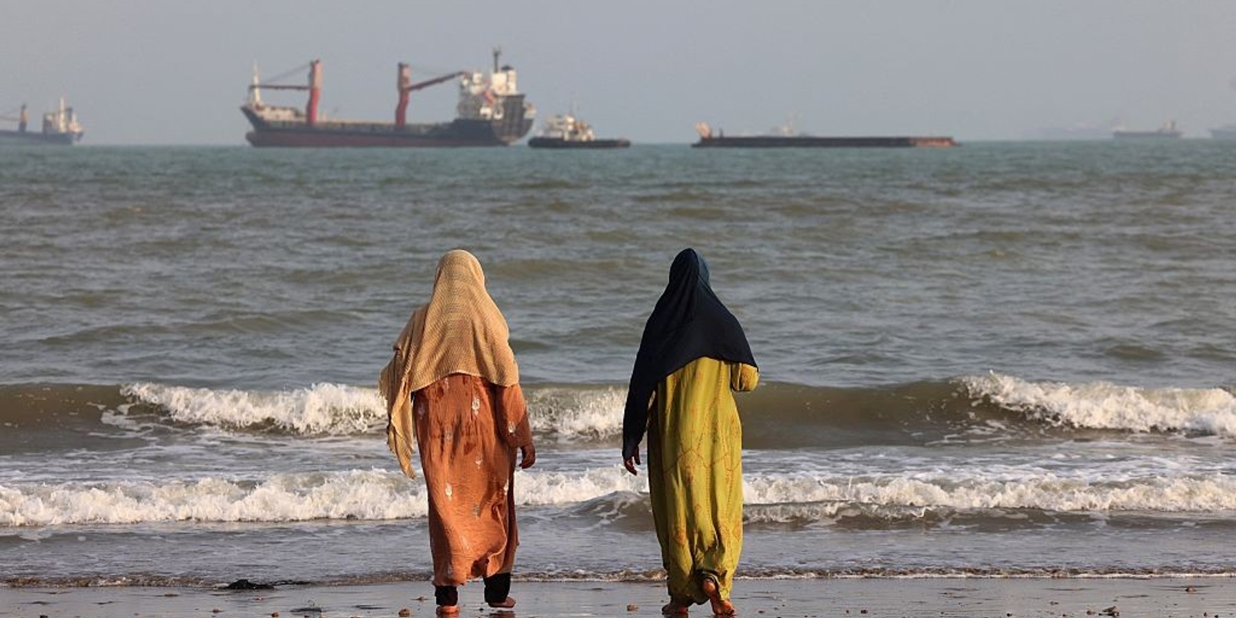 IRAN-US-ISRAEL-WAR-DAILYLIFE Iranians enjoy the seashore as vessels are seen in the Strait of Hormuz off Bandar Abbas, in southern Iran on August 10, 2026. The US President signalled on August 9 that he was prepared to let economic pressure mount against Iran, apparently backing away from more military strikes after Tehran issued a list of demands for opening the Strait of Hormuz. His remarks came after Iran issued over the weekend a list of conditions to reopen the Strait of Hormuz, which has remained largely closed since the start of the Middle East war in late February. (Photo by Atta KENARE / AFP via Getty Images) /