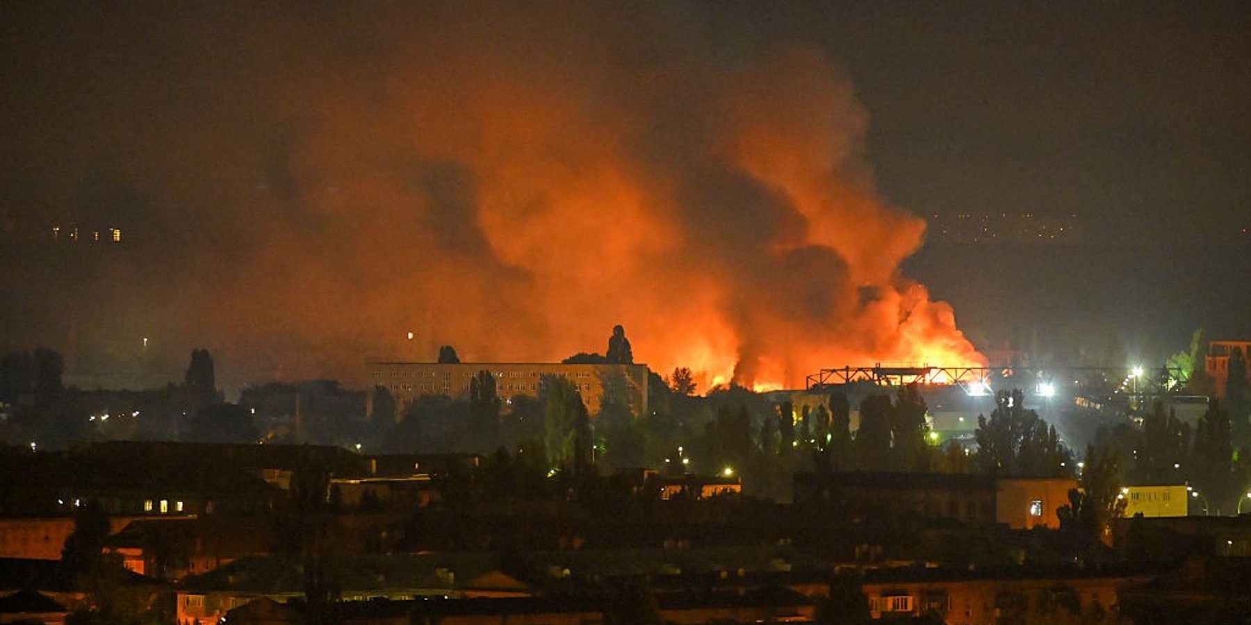 Large fire with thick smoke engulfing buildings at night.