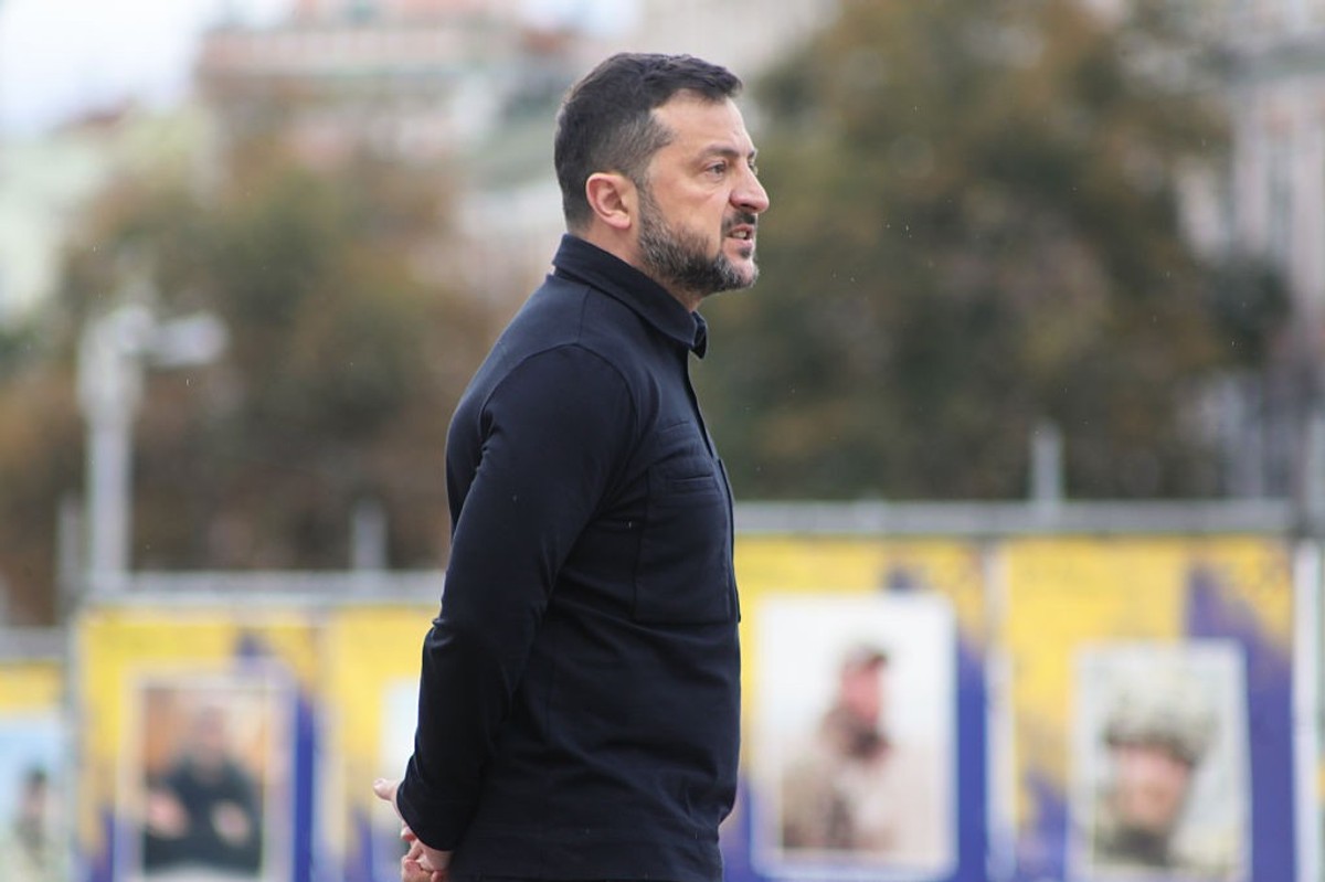 Man in black jacket standing outdoors with blurred background.