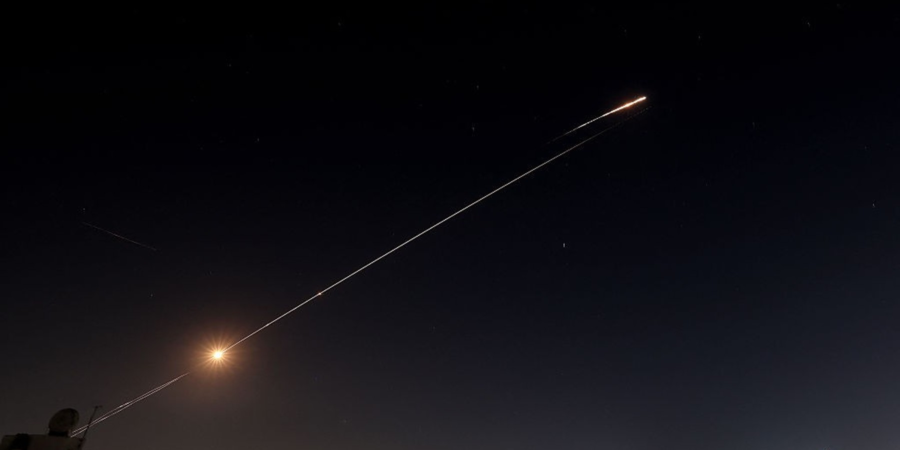 Nighttime view of city with streaking lights in the sky.