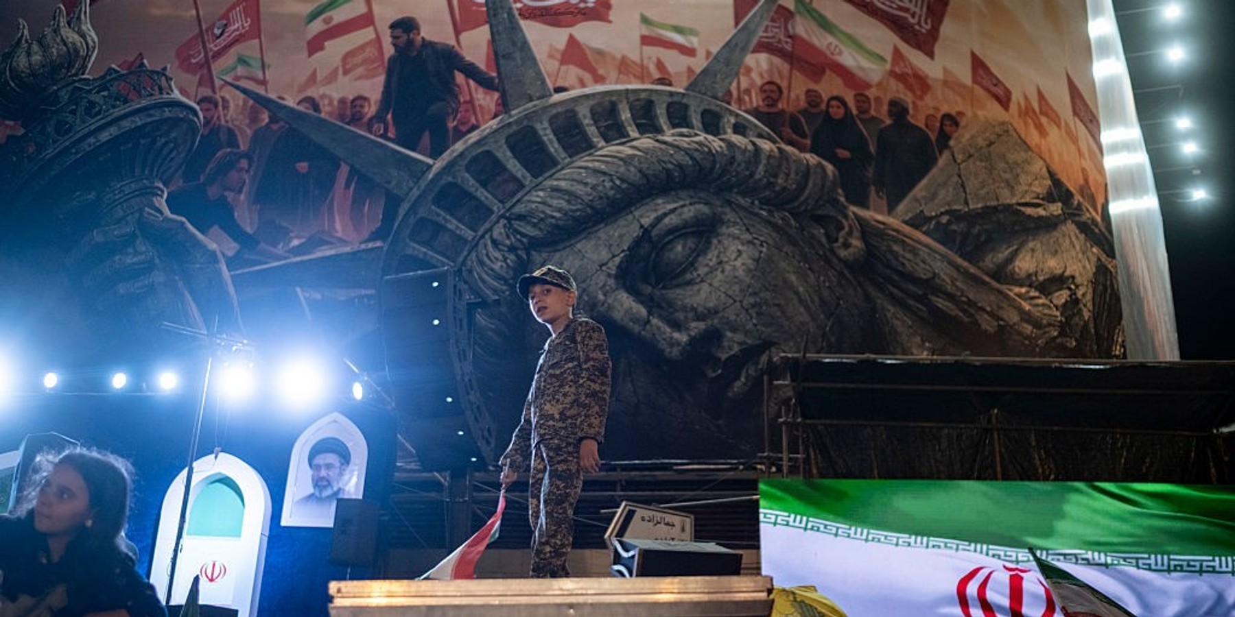 Pro-Government Rally In Tehran, Iran An Iranian schoolboy wearing an Islamic Revolutionary Guard Corps (IRGC) uniform holds a national flag while standing beneath an anti-U.S. billboard during a nightly pro-government rally in downtown Tehran, Iran, on August 30, 2026. U.S. forces strike two Iranian military launchers on Larak Island in the Strait of Hormuz on August 30, in the first reported U.S. attack on Iranian territory since late July. (Photo by Morteza Nikoubazl/NurPhoto via Getty Images)