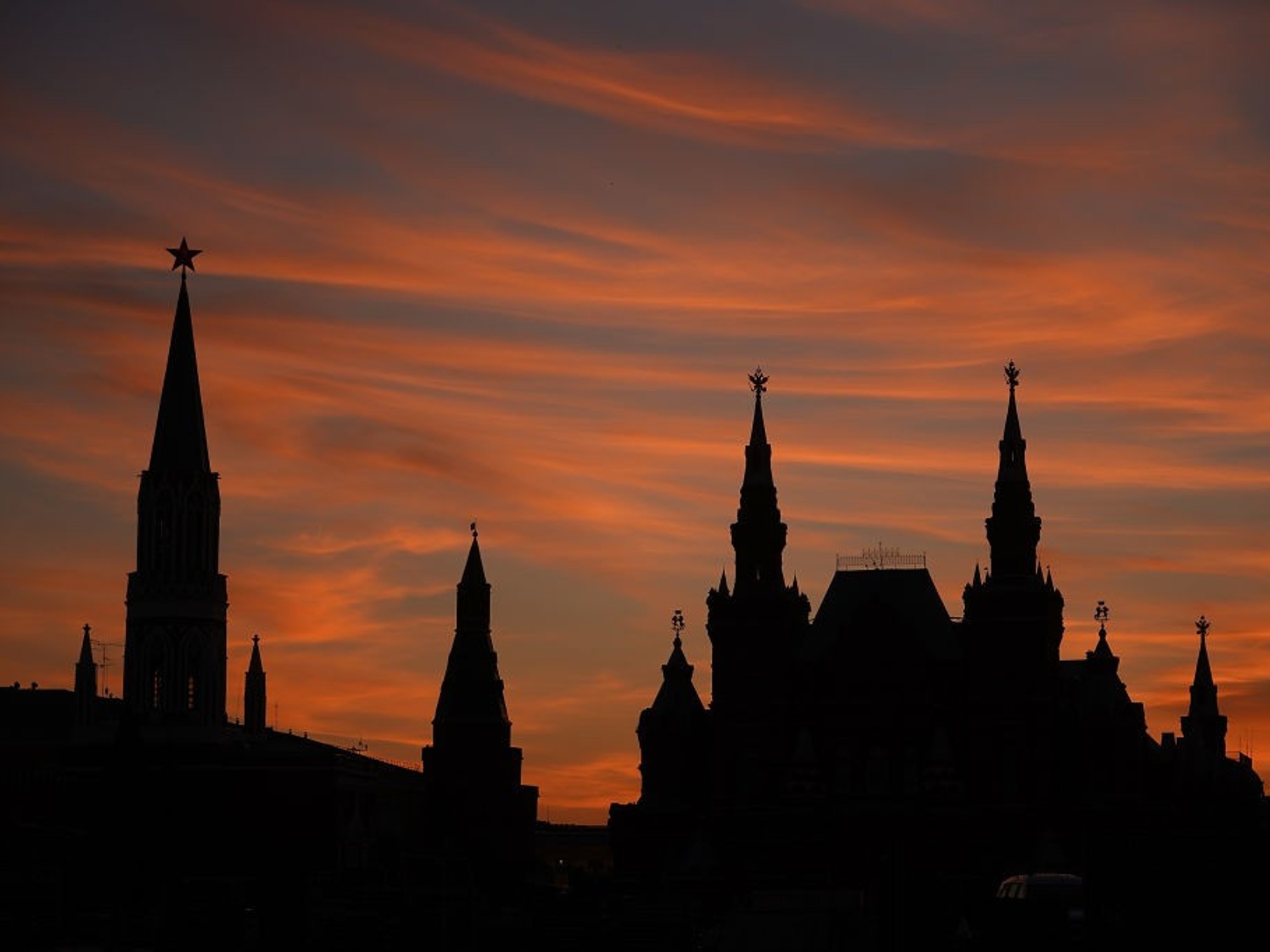 Silhouette of towers against a vibrant orange sunset sky.