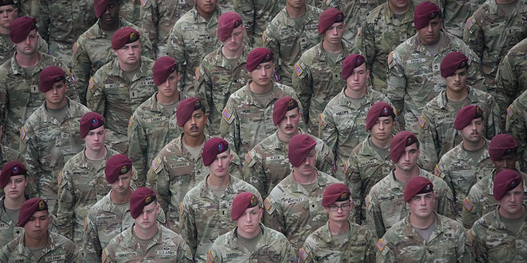 Soldiers in camouflage uniforms and maroon berets standing in formation.