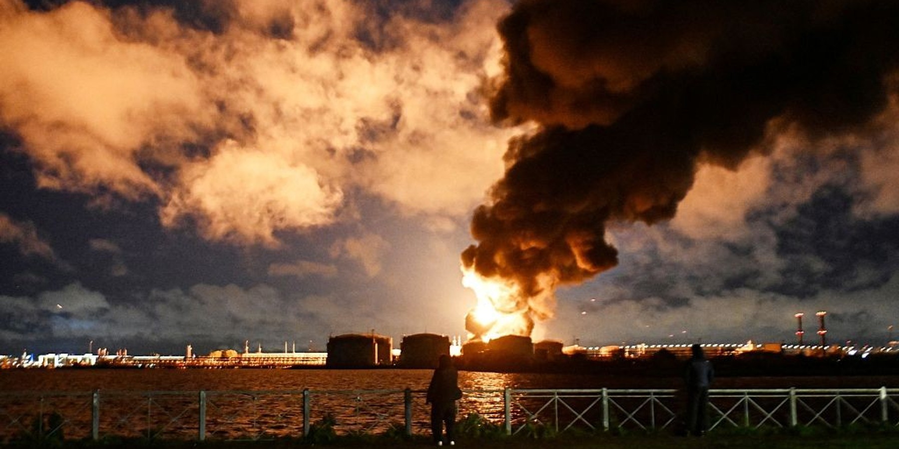 TOPSHOT-RUSSIA-UKRAINE-CONFLICT TOPSHOT - People watch the burning oil terminal following an air attack in Saint Petersburg on October 18, 2026, amid the ongoing Russian-Ukrainian conflict. Russia shot down dozens of Ukrainian drones near Saint Petersburg, authorities said on October 18, 2026, with an oil terminal hit and flights disrupted at one of the country's busiest airports. (Photo by AFP via Getty Images)