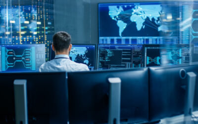 Back View in the System Control Center Operator Working. Multiple Screens Showing Technical Data.